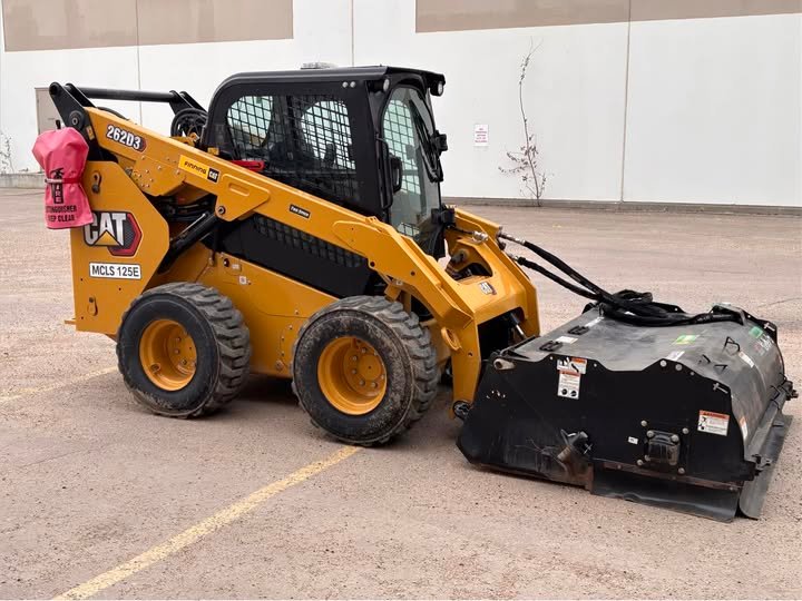 Matt's CLS CAT skid steer with sweeper attachment on a commercial parking lot